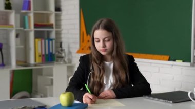 Sınıfta ders kitabı yazan neşeli çocuk, bilgi sahibi..