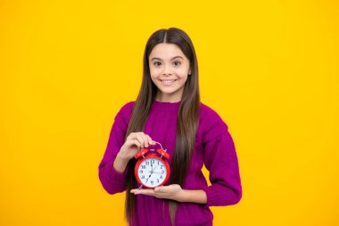 Çocuk saati sarı stüdyo arka planında izole edilmiş. Alarm saati olan genç çocuk saati gösteriyor