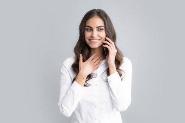 Gülümseyen esmer iş kadını cep telefonuyla konuşuyor. Akıllı cep telefonuyla izole edilmiş gri arka plan sohbeti yapan genç kadın.
