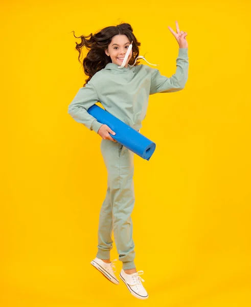 Teenage girl in track suit, fashion sports wear isolated on yellow background. Fitness sport child in sportswear sports clothing and shoes