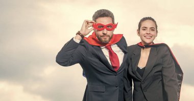 Gökyüzü arka planında süper kahraman kıyafetli neşeli bir çift..