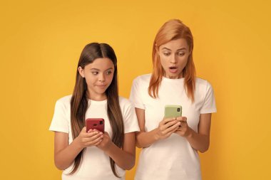 Şok olmuş kadın ve kız internette sohbet ediyor. Aile blogu. Alışveriş uygulaması. Modern iletişim teknolojisi. Anne-kız yazışıyor ve mesajlaşıyor. SMS ve anlık mesajlaşma. anne ve çocuk blogcuları akıllı telefon kullanıyor.