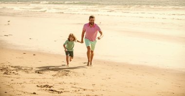 Çocuk ve babası yaz tatilinde plajda koşuyorlar, tatile gidiyorlar..