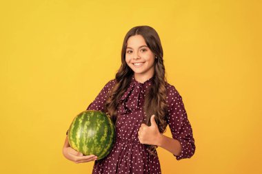 Mutlu genç kız taze olgun karpuz meyvesi tutuyor baş parmağını kaldırıyor, yaz..