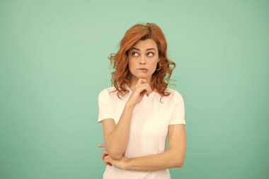 Mavi arka planda kıvırcık saçlı kızıl saçlı bir kadın..