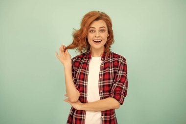 Mavi arka planda kareli tişörtlü, şaşkın kızıl kız..