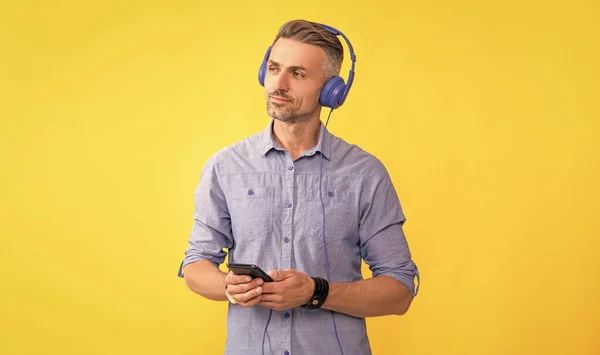 man listen music and hold phone. modern life and lifestyle. guy chatting in earphones. musical playlist. mobile music application. new app. guy in headphones use smartphone.