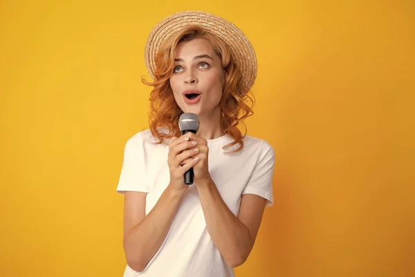 Beautiful young woman singing karaoke isolated on yellow. Girl singing soundtrack song at mic