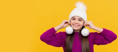 Sarı arka planda kartopları olan şapkalı neşeli çocuk. Noel çocuğu, stüdyo çocuğu kışın fotokopi çekilen portresi