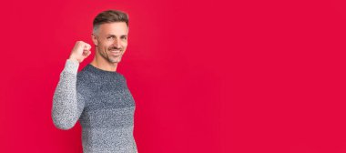 Kırmızı arka planda süveter giyen başarılı adam, başarı. İnsan yüzü portresi, kopyalama alanı olan pankart