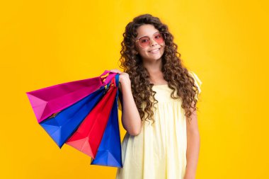 Yaz alışverişi. Sarı arka planda alışveriş torbaları olan güzel moda kızı. Alışveriş ve moda alışverişi. Alışveriş çantalı çocuk. Gülümseyen kız