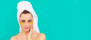 Genç kızın yüzünde havluyla kolajen altın göz bantları var. Güzel kadın, izole edilmiş yüz portresi, taklit alanı olan pankart.