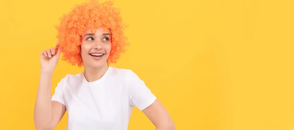 パーティーの楽しみのウィッグ 黄色の背景にオレンジの髪のウィッグを身に着けている空想的な外観を持つ陽気な面白い女の子 クール 女性の孤立した顔の肖像画 コピースペースのバナー — ストック写真