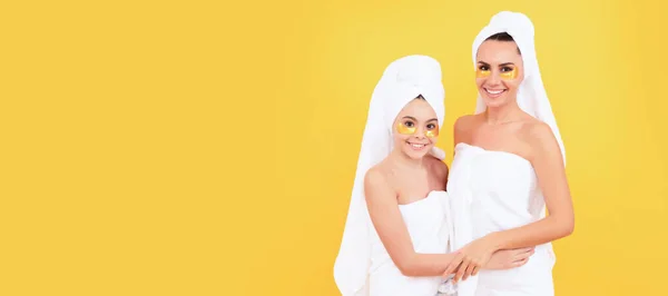 Mother and daughter child banner, copy space, isolated background. moisturizing skin. cosmetology. mom and daughter in terry towel use patch. beauty day in family spa