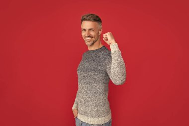 Kırmızı arka planda kazaklı mutlu adam, başarı..