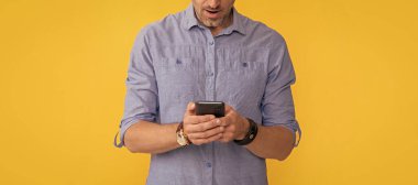 Afallamış bir adam sarı arka planda telefonla konuşuyor..