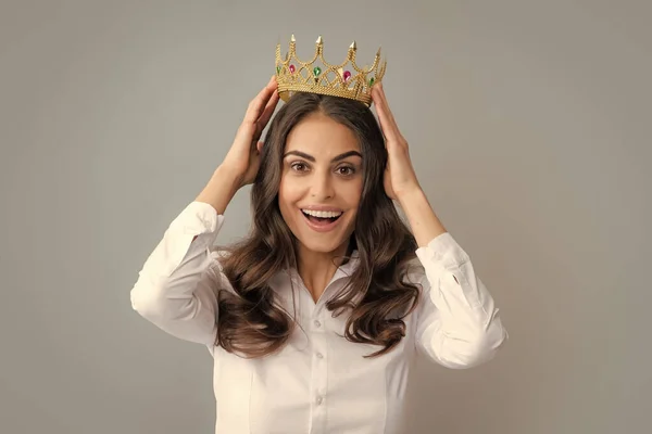 Portrait of arrogance woman with golden crown on head, leadership and success. Attractive rich arrogant girl wearing crown isolated over gray background