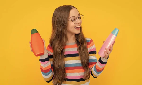 daily habits and personal care. skin lotion care beauty. presenting cosmetic product for teen. kid in glasses make choice of shower gel. happy teen girl use shampoo bottle. child with hair conditioner