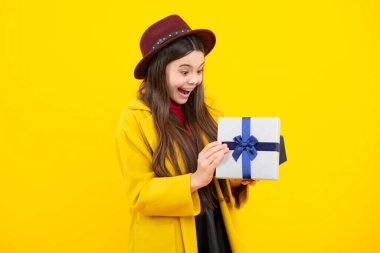 Sarı izole edilmiş arka planda hediye kutusu tutan ergen bir çocuk. Çocukların doğum günü hediyesi. Noel ya da yeni yıl hediyesi. Heyecanlı bir genç, şaşkın ve neşeli duygular içinde