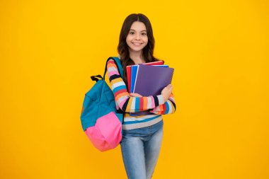 School girl hold copybook and book on yellow isolated studio background. School and education concept. Teenager girl in school uniform. Happy teenager, positive and smiling emotions of teen girl