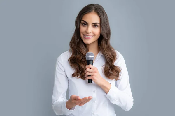 Public speaking with microphone, speaker speech presentation concept. Beautiful stylish woman singing karaoke isolated over gray background