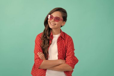 Neşeli genç kız güneş gözlüklü ve günlük gömlekli uzun kıvırcık saçlarıyla el ele tutuşuyor..