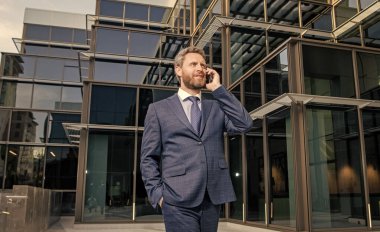 İş elbisesi içinde başarılı bir girişimci ofis dışında telefon görüşmesi yapar, sohbet eder..