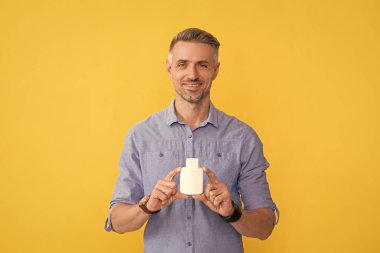 Adam ilaç alıyor. Tıbbi reklam. Enerji ilacı sunan adam. Günlük vitaminler ve takviyeler. Erkek ağrı kesici veriyor. Mutlu adam kavanozu ilaç haplarıyla birlikte tutuyor. Uyuşturucu işi.