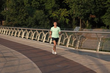 Spor kıyafetleri içinde koşan atletik bir adam..