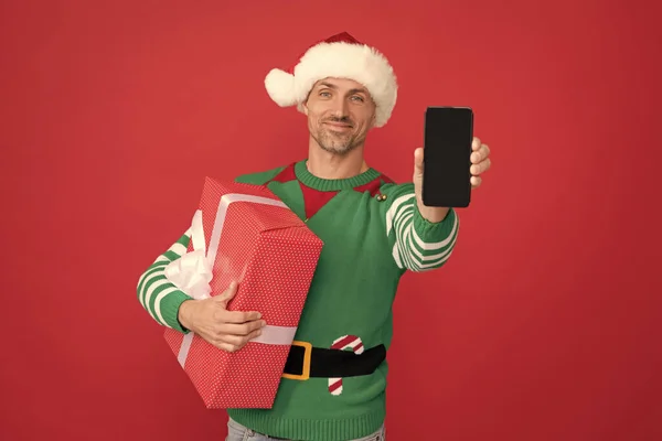 Szczęśliwy Elf Człowiek Kapeluszu Świętego Mikołaja Prezentujący Smartfon Pudełkiem Czerwonym — Zdjęcie stockowe
