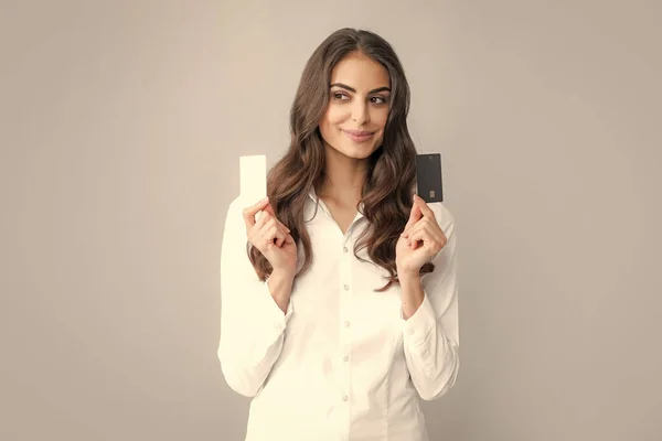 Photo of pleased young woman posing isolated over gray background holding debit credit card