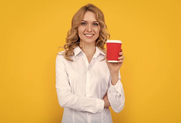 smiling blonde woman with coffee cup on yellow background.