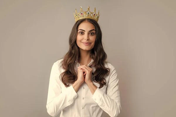 Portrait of arrogance woman with golden crown on head, leadership and success. Attractive rich arrogant girl wearing crown isolated over gray background