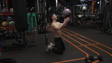 Sporcuda spor salonunda spor yaparken, spor salonunda. Sporcunun spor salonunda top egzersizi var. Sporcu topuyla spor salonu egzersizi..