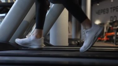 Spor ayakkabılı atletik ayaklar spor salonunda spor salonunda koşuyor. Koşu makinesi fitness çalışması. Beden eğitimi için spor malzemeleri. Kardiyo eğitimi.