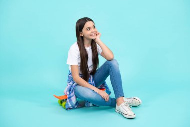 Kaykaylı genç kız. Moda çocuğu mavi arka planda moda tarzında. Mutlu ergen, pozitif ve gülümseyen genç kız duyguları