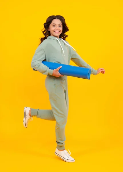 Teenage girl in track suit, fashion sports wear isolated on yellow background. Fitness sport child in sportswear sports clothing and shoes