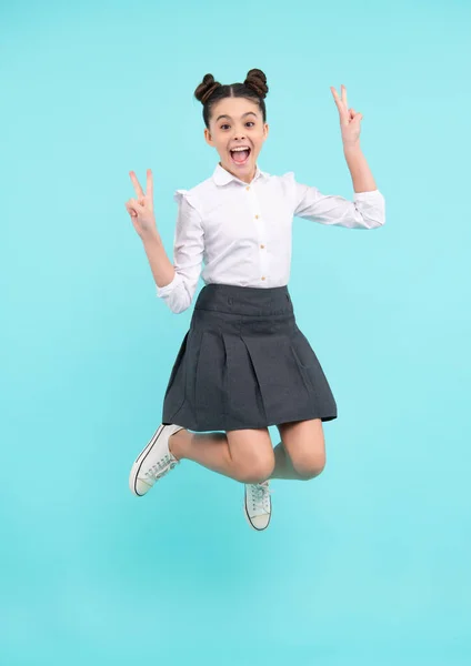 Amazed teenager. Full length cheerful teenager kid jump enjoy rejoice win isolated on blue background. Small child girl in summer dress jumping. Excited teen girl