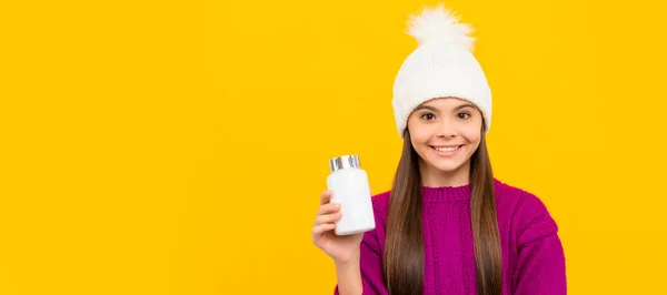 冬の帽子の子供の笑顔を丸薬瓶で 栄養補助食品 天然の丸薬を持った10代の少女 孤立した子供の顔 バナーヘッダー コピースペースの水平ポスター — ストック写真