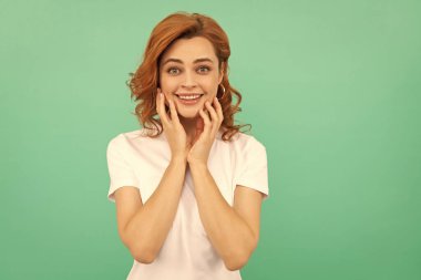 Genç bir kızın güzel görünüşü. Mavi arka planda kızıl saçlı kadının portresi. Olumlu duygularını ifade et. Kıvırcık saçlı neşeli bir kadın. Güzellik ve moda. Kadın model..