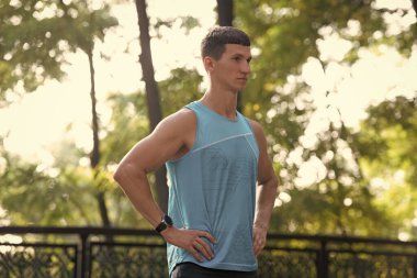 Spor giyimli, elleri kalçasında kaslı atletik bir adam..