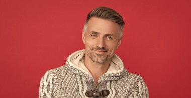 Kırmızı arka planda gri kazaklı, fotokopi alanı olan, saç stili pozitif adam..