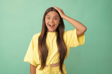 express positive emotions. shocked kid with long hair. beauty and fashion. female fashion model. pretty look of young girl. face portrait of child on blue background.