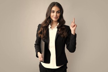 Genç güzel bayan öğretmen ya da gri stüdyo arka planında izole edilmiş mutlu öğrenci. Dizüstü bilgisayarlı üniversite öğrencisinin portresi. Dizüstü bilgisayarda çalışan kadın, serbest çalışan.