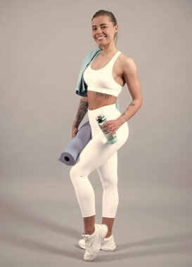 Gri arka planda soyutlanmış spor elbiseli neşeli bir kadın vücudu. Sağlıklı, güzel sporcu kadın.