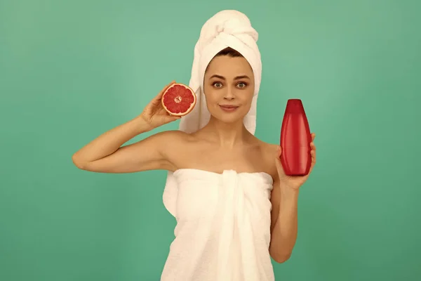 Glimlachende Jonge Vrouw Handdoek Met Grapefruit Shampoo Fles Blauwe Achtergrond — Stockfoto