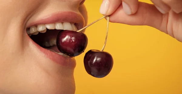 Womans enjoying fresh sweet cherry. Female mouth eating sweet cherry. Closeup female mouth tasting sweet cherry