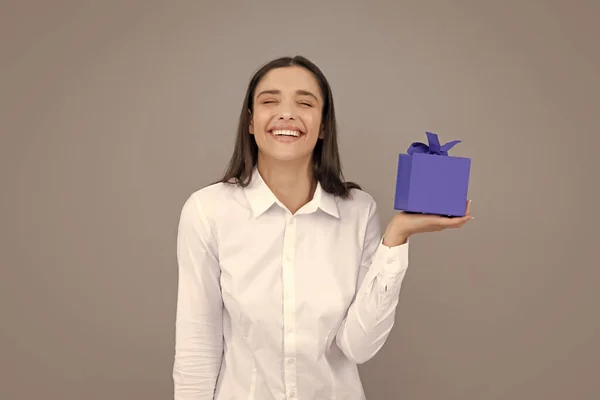 Woman with gift. Portrait of excited young girl holding gift box, isolated grey background. Pretty girl with present