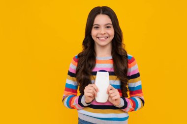 Teenager child girl with bottle shampoo conditioners or shower gel. Kids hair care. Hair cosmetic product, shampoo bottle. Happy teenager, positive and smiling emotions of teen girl