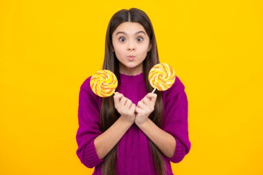 Hippi ergen kız lolipopu yalıyor. Şeker, şeker ve şekerleme. Çocuk lolipop şekeri yiyor. Genç bir kızın şaşırmış duyguları.
